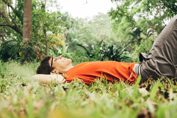 Relaxed man with resting in a forest. Young man breathing deep fresh air outdoor.