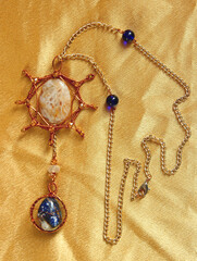 Sun and Earth pendant handmade from natural stones (agat, sodalite, carnelian) and copper wire on golden fabric.