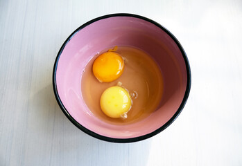 Two yolks from eggs of different yellow colors in one plate. Ingredient for cooking and baking