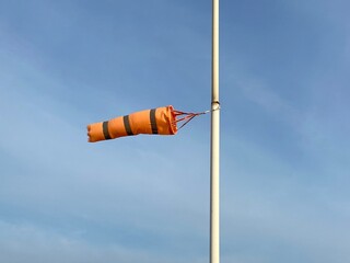orange airport wind sock on blue sky straight out against blue 