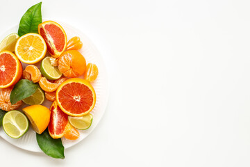 Layout of citrus fruits on white plate top view