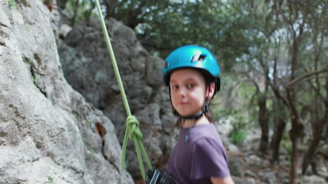 Children's rock climbing. The boy is riding a rope. Extreme hobby. An athletic child trains to be strong. Climbing safety.