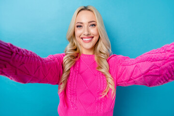 Fototapeta premium Photo of toothy beaming lovely girl with wavy hairdo dressed pink sweater doing selfie recording video isolated on blue color background