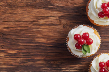 Red currant cupcakes on textured wooden background