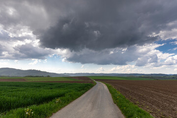 Fototapeta na wymiar Regenwolken mit einsamer Strasse zum Horizont