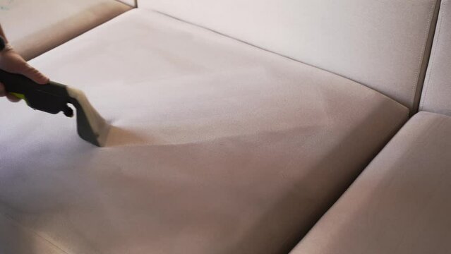 4k video line on couch after spraying water of dry cleaning extractor machine. Domestic cleaning service cleaner is removing dirt and dust from couch using dry cleaning extraction machine.