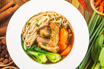Spicy red soup beef noodle in a bowl on wooden table