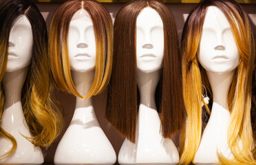 Multi-colored wigs are worn on the heads of mannequins.