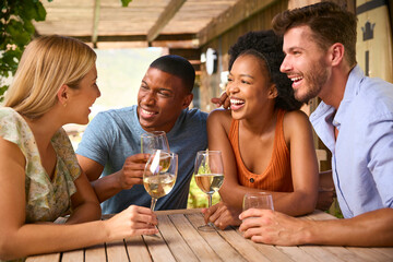 Group Of Smiling Multi-Cultural Friends Outdoors At Home Drinking Wine Together