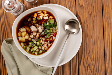 Sliced vegetables and meat for okroshka are laid out in a plate