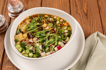 Sliced vegetables and meat for okroshka are laid out in a plate