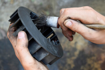 Engine Cylinder Blowing Impeller for Scooter. The guy cleans the part from dirt with a brush.