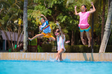 Kids jump into swimming pool. Summer water fun.