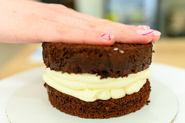 A woman's hand keeps her hand on a chocolate cake at home.