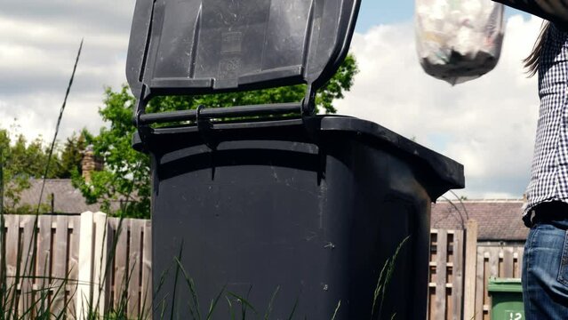 Woman puts garbage in the wheelie bin wide shot