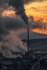 Factory with chimney and smoke and steam with colorful sunset at background