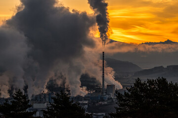 Smoke and steam from factory with chimney and colorful sky at background