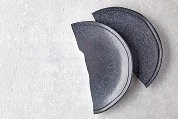 Two halves of a broken ceramic plate on a gray concrete table