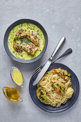 Chkmeruli on a dark plate with cutlery and gravy boats with oill and milk cream. Plate of spaghetti with fried chicken