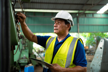 Asian worker working in factory using laptop to check safety in factory. Industrial safety concept. Asian engineer working in a factory. Maintenance Work in the factory.