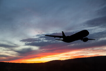 Airplane taking off at the sunset sky.
