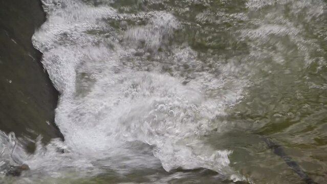 The water flows through the concrete weir with the gentle sound of water flowing and the beautiful singing of birds. Create a peaceful atmosphere filled with the beauty of nature.close up. slow motion