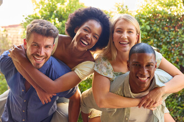 Portrait Of Multi-Cultural Friends On Holiday With Men Giving Women Piggybacks