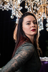 Brunette in a dark dress on the background of a chandelier