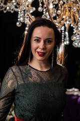Brunette in a dark dress on the background of a chandelier
