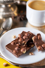 Milk chocolate with hazelnuts on a white saucer