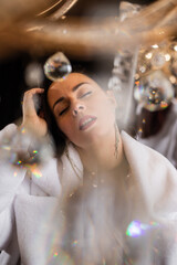 Brunette with red lipstick in a white fur coat on the background of a chandelier