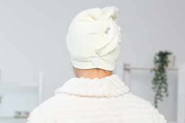 Woman make wrapped in a towel drying her hair after a morning shower. Hair care and body skin...