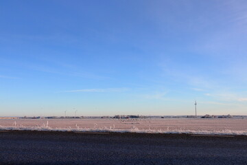 Sparse snowy field and a dark asphalt road. Near Skara, Sweden, Scandinavia, Europe. 