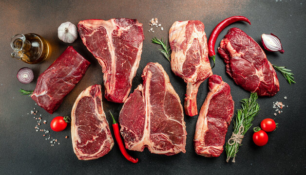 Variety of Raw Black Angus Prime meat steaks T-bone, tomahawk, New York steak. Set raw marbled beef strip loin steaks. place for text, top view