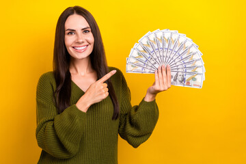 Portrait of positive successful girl direct finger hand hold dollar bills banknotes isolated on yellow color background