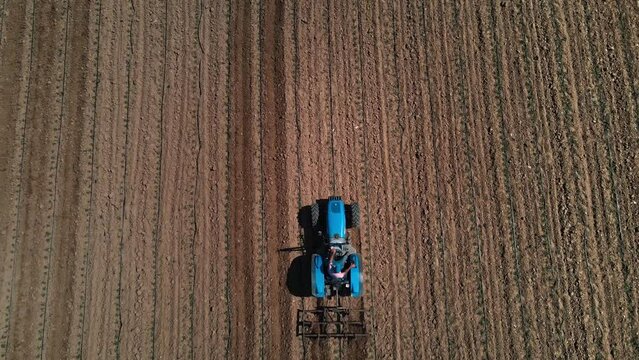 Aerial top down view of a tractor harrowing an agriculture field in spring. tractor plows the field top view
