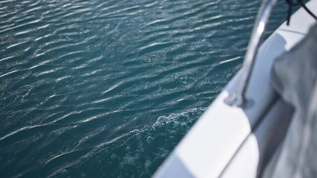 boat goes towards the shore on the waves of the ocean with wonderful reflections of the reflected sun. A wonderful moment of a romantic sea trip by speed boat in summer day.