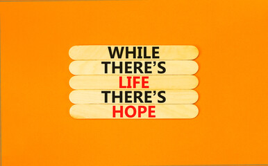Life and hope symbol. Concept word While there is life there is hope on wooden stick. Beautiful orange table orange background. Business lifestyle life and hope concept. Copy space. © Dzmitry