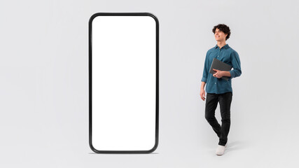 Man With Laptop Posing Near Large Phone On White Background