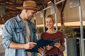 Beautiful blond woman and a farmer standing in a stall for inspection.