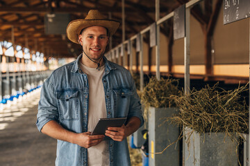 A handsome farmer standing in a stall.