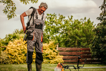 Handyman preparing for cutting the grass with a string trimmer. Copy space