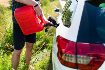 The car parked on the side of the road, the driver refuels the car from the canister. Help on the...