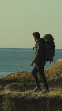 The man with backpack walking on the mountain against the seascape