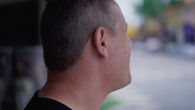 Man standing in street observing urban neighborhood. 40s middle aged male person looking at sidewalk in front of storefront