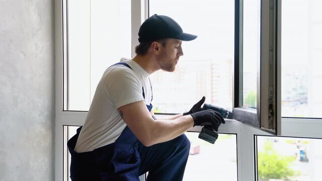 Service man in uniform installs pvc windows in new hotel room