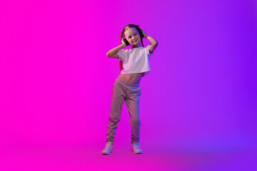Cute summer little girl using wireless headphones on luminous background