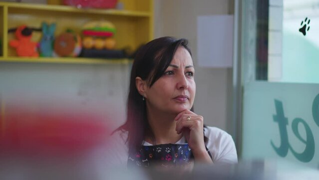 One pensive Female Entrepreneur of Local Shop thinking behind counter with thoughtful expression. A young Petshop owner in contemplation and hand in chin