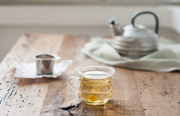 Freshly made white tea on a weathered wooden board with vintage teapot in the background