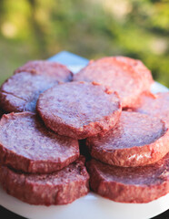 Process of cooking and grilling beef burgers on open-air street food festival, view of chef hands in gloves with variety of ingredients on grill stove, family burger picnic at summer terrace
